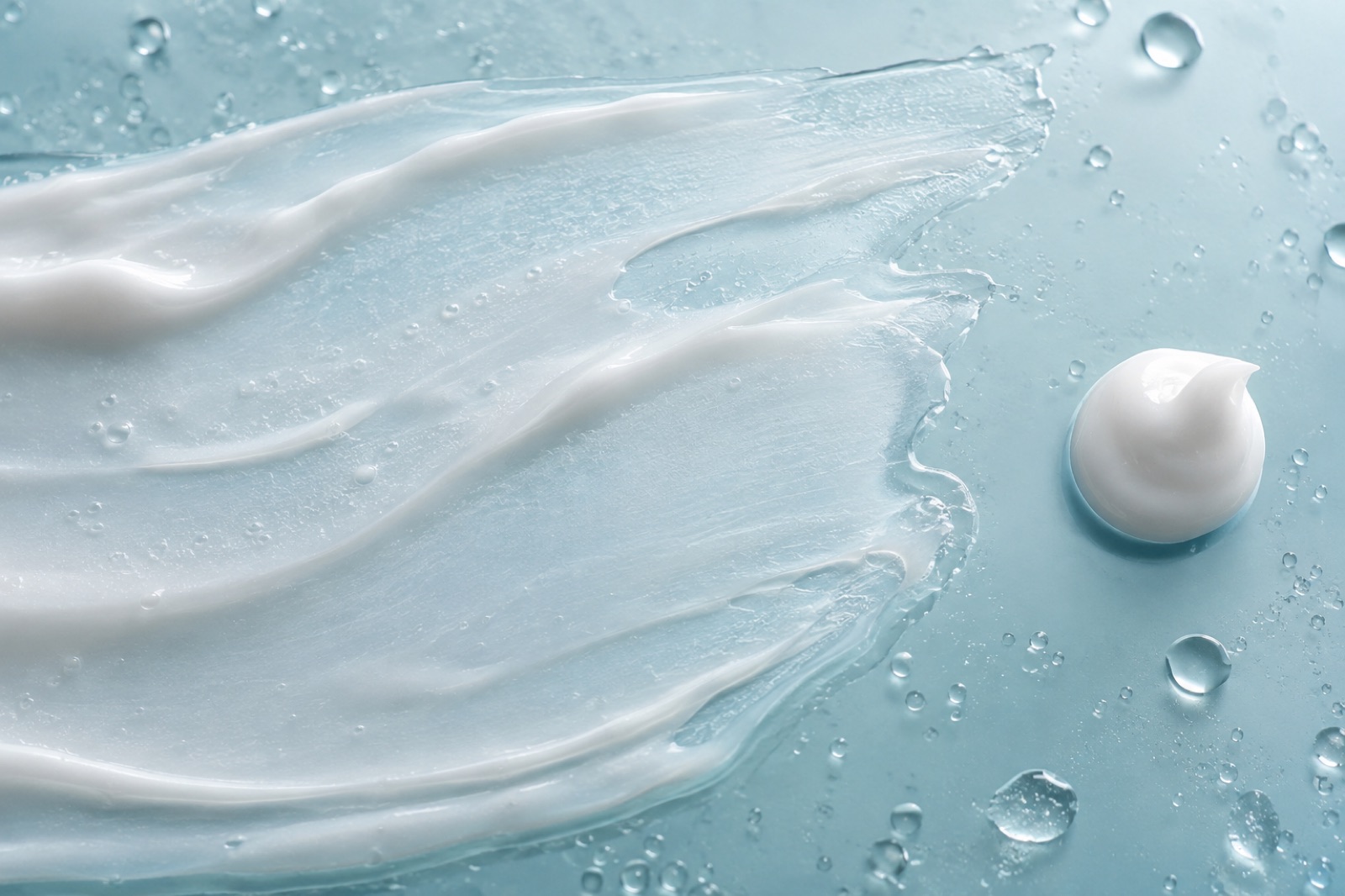 A long brushstroke-like smear of white lotion across a blue surface, with a small mound of lotion squeezed out on the right