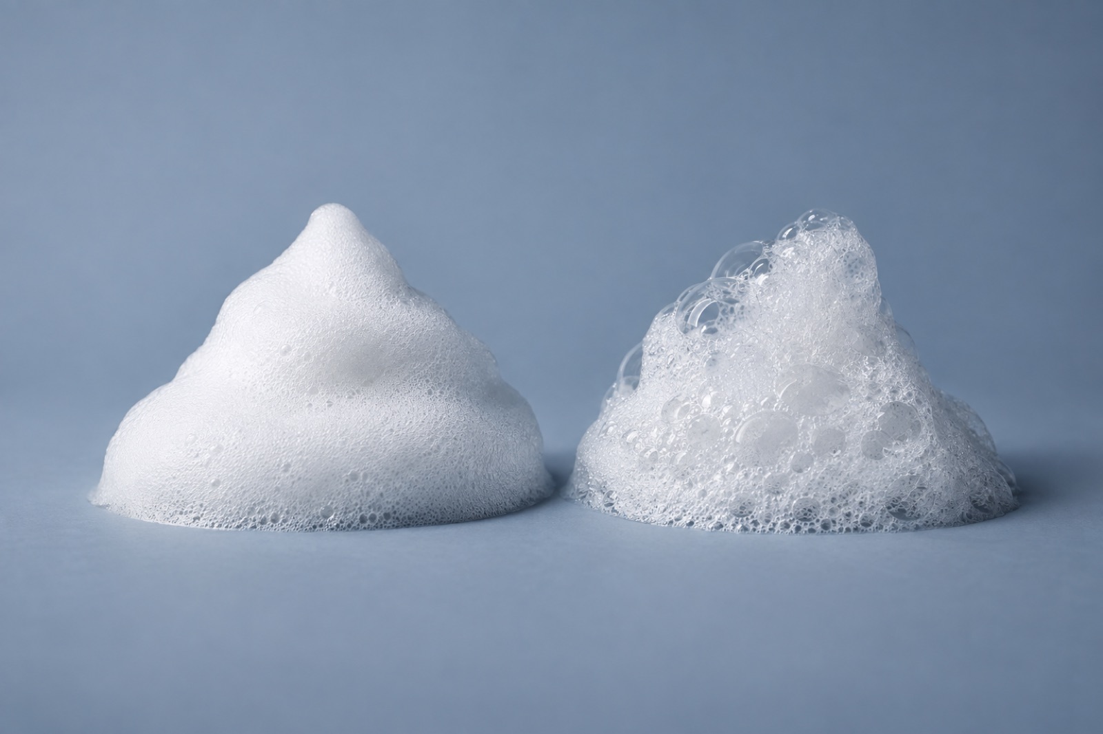 Two mounds of foam on a blue-gray background, fine smooth white foam on the left and loose foam with large bubbles on the right