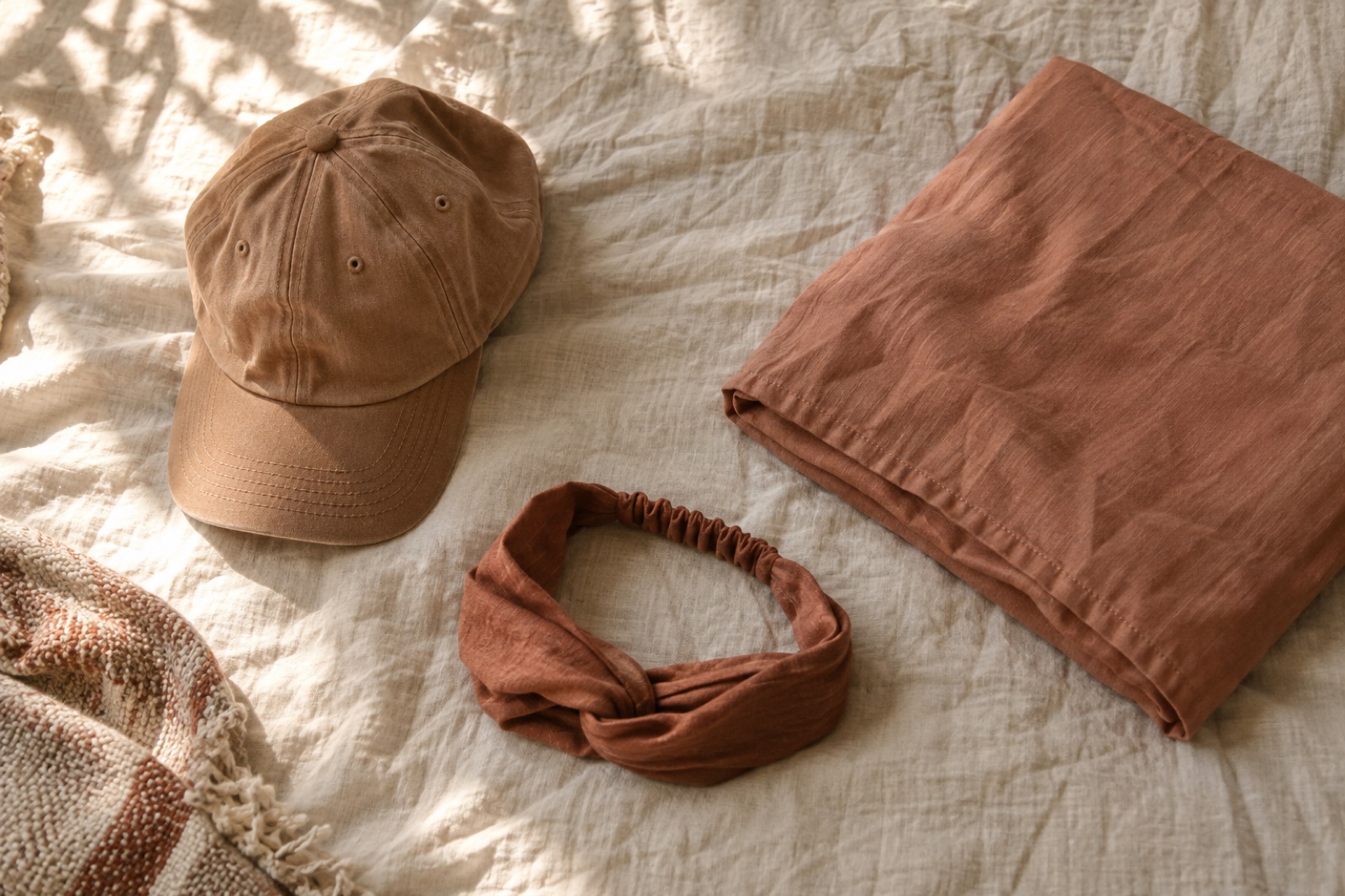 Kulay okreng baseball cap, headband na may buhol at nakatiklop na brick-red na punda na nakakalat sa gusot na puting kobre-kama